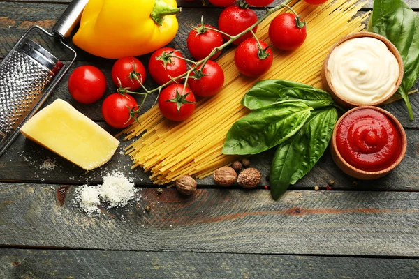 Těstoviny špagety s rajčaty, sýrem a bazalkou na rustikální dřevěné pozadí — Stock fotografie