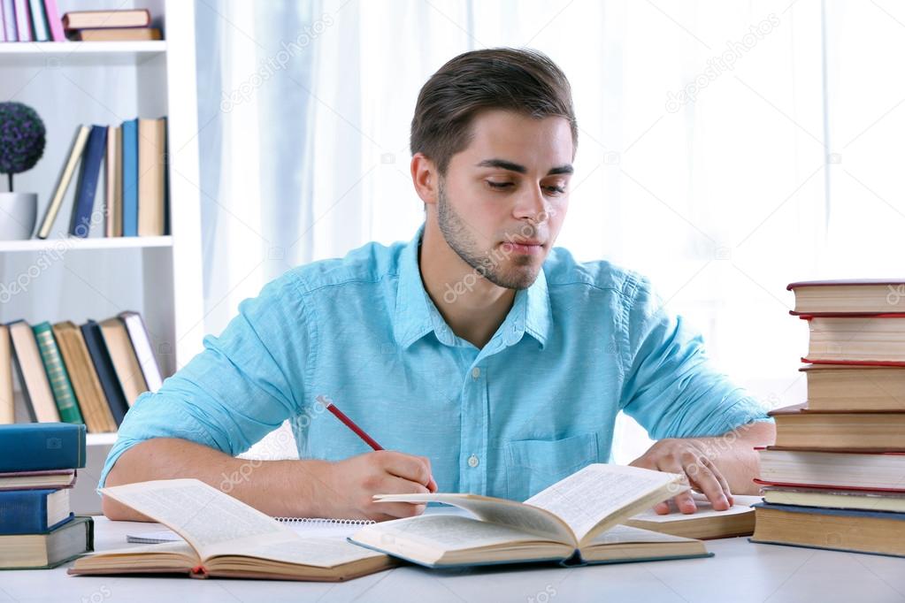 Young man reading book at table