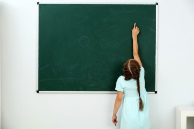 Küçük kız kara tahta bir şeye işaret