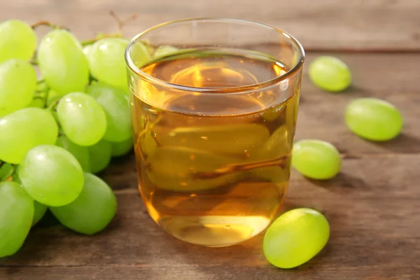 Vaso de jugo de uva sobre mesa de madera —  Fotos de Stock