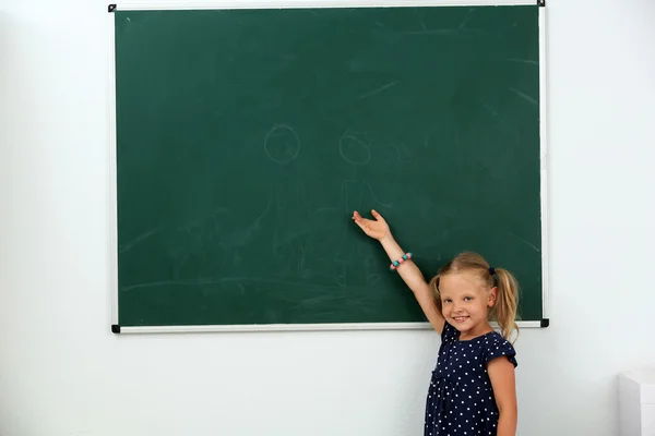 Little girl pointing at something at chalkboard