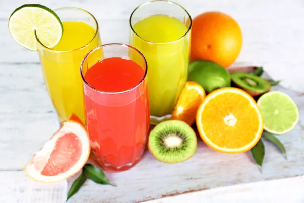 Glasses of different juice with fruits and mint on table close up — Stock Photo, Image