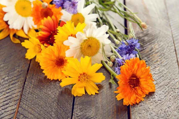 Flores silvestres brilhantes na mesa de madeira — Fotografia de Stock