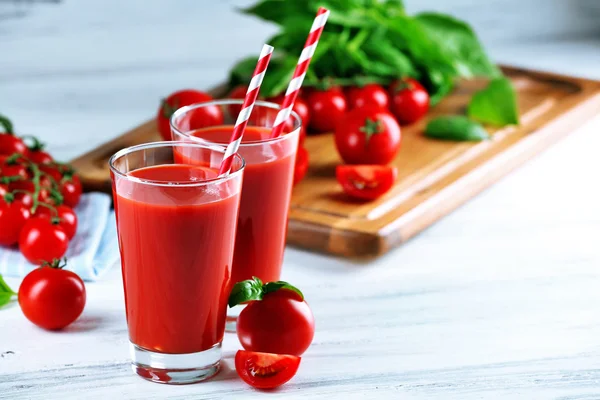 Стаканы томатного сока с овощами на деревянном столе — стоковое фото
