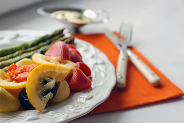 Жареная спаржа и вкусная красочная макароны с овощами на тарелке на фоне деревянного стола — стоковое фото