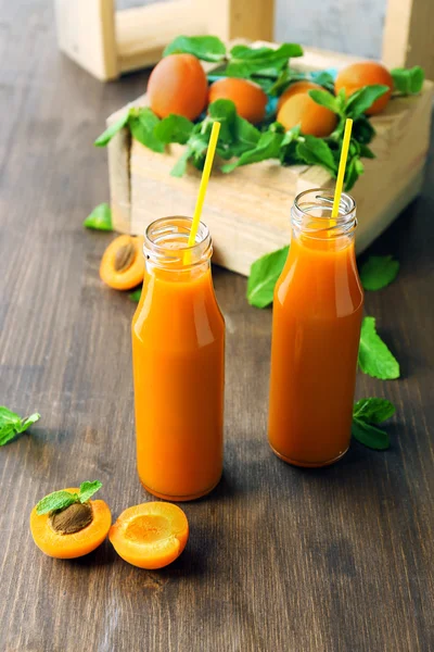 Bottles of apricot juice and fresh fruits on table close up — Stock Photo, Image