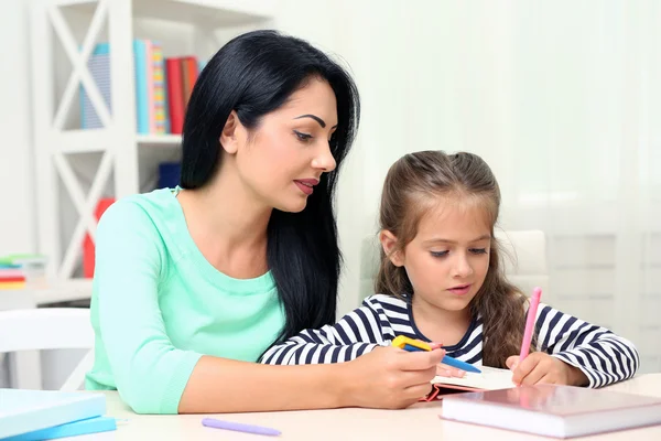 Schulmädchen macht Hausaufgaben mit Mutter — Stockfoto