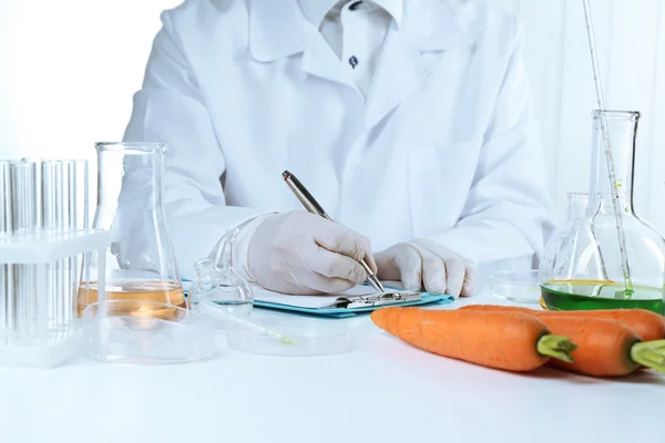 Cientista examina cenouras — Fotografia de Stock