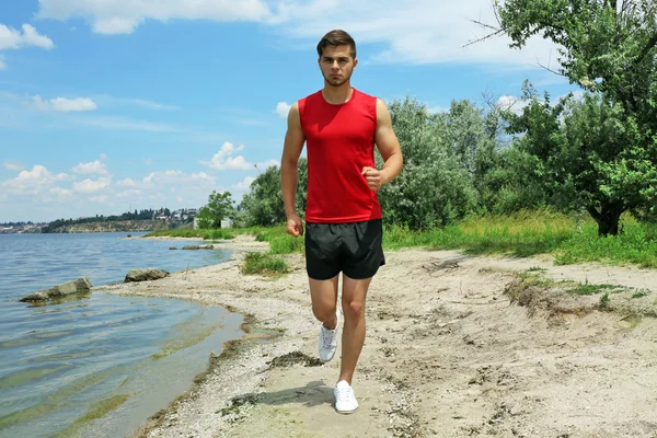 Ung man joggar på stranden — Stockfoto