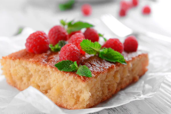 Fresh pie with raspberry on parchment on wooden table, closeup — Stock Photo, Image