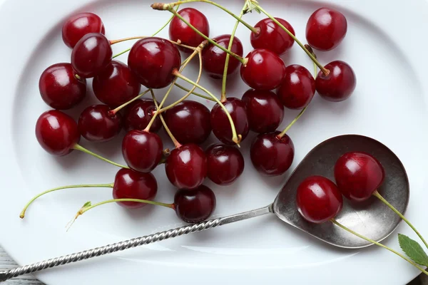 Cerises douces sur assiette, sur fond bois — Photo