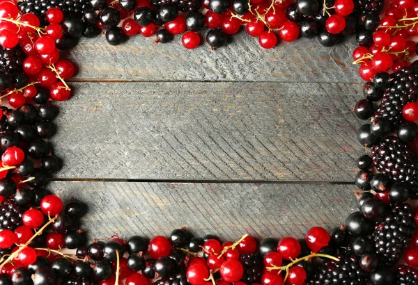 Rijpe rode en zwarte bessen op houten achtergrond — Stockfoto