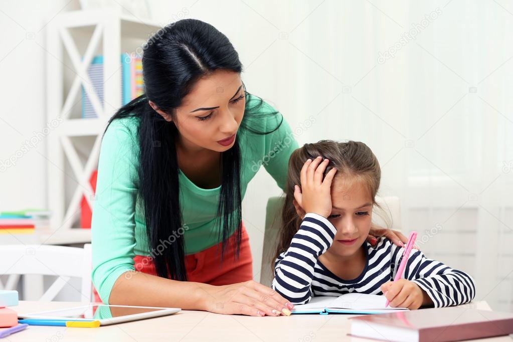 School girl doing homework with mother 