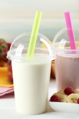 Milkshake hafif ahşap arka plan üzerinde plastik bardak