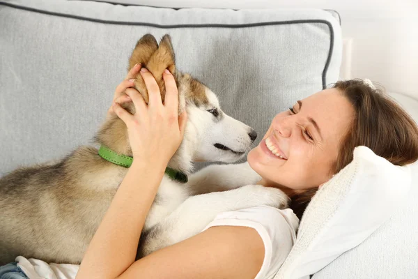 Jeune femme couchée avec chien malamute — Photo