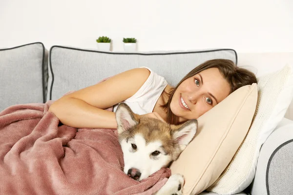 Jonge vrouw liggend met malamute hond — Stockfoto