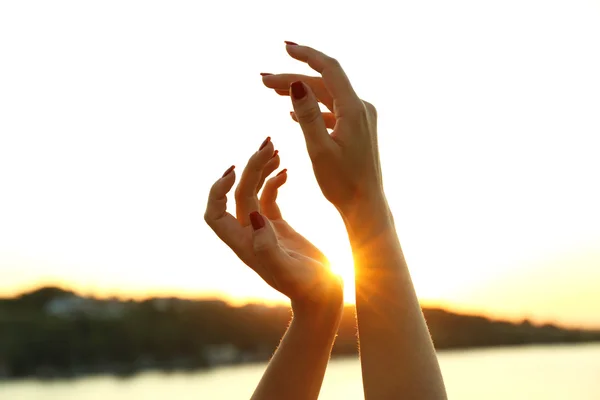 Mãos femininas no céu ensolarado — Fotografia de Stock
