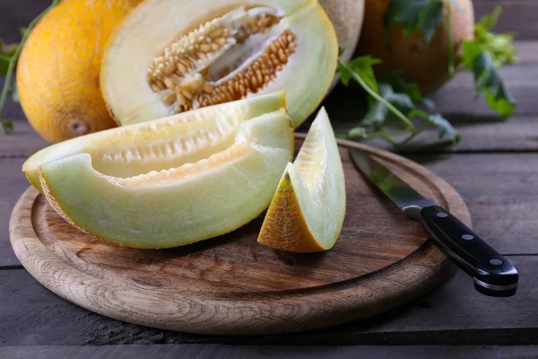Ripe melons with green leaves on wooden table close up — Stock Photo, Image