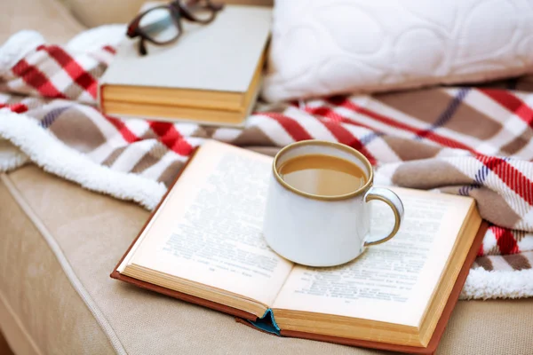 Taza de café con libro en sofá en la sala de estar — Foto de Stock