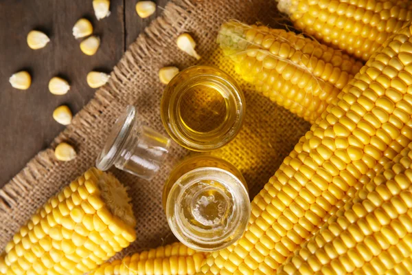 Fresh corn with bottles of oil on table close up — Stock Photo, Image