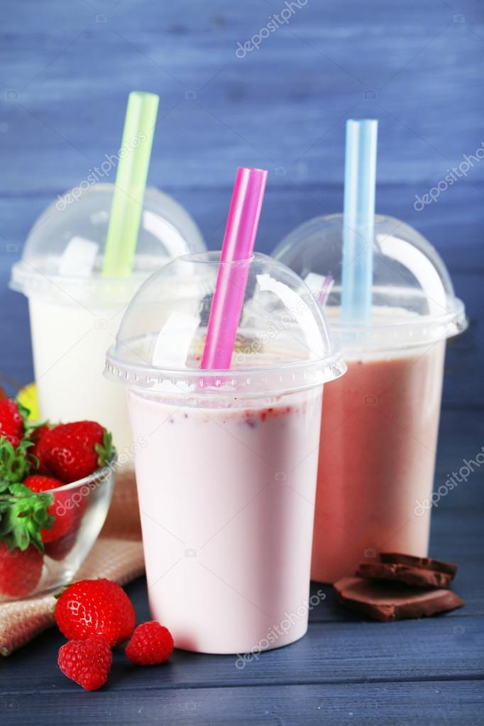 Plastic cups of milkshake on color wooden background Stock Photo by ©belchonock 82524058