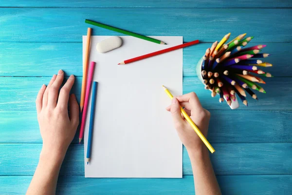 Рука с цветными карандашами и чистым листом — стоковое фото