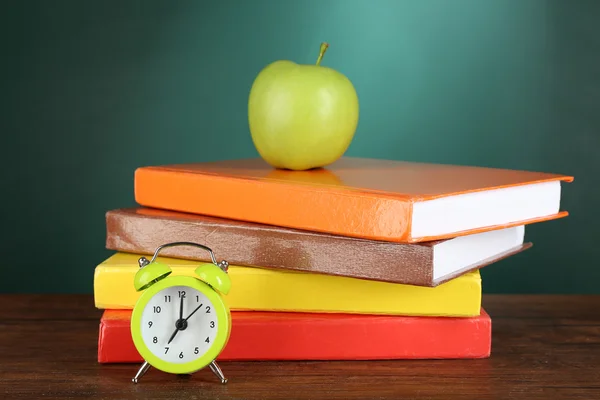 Книги з зеленим яблуком і будильник — стокове фото