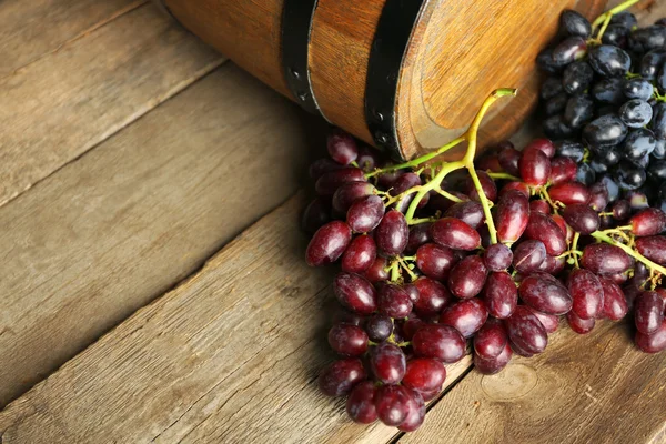 Old wine barrel and grape on wooden background — Stock Photo, Image