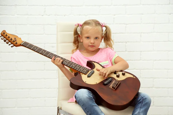 En liten flicka som spelar gitarr — Stockfoto