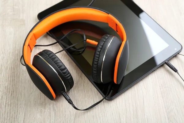 Headphones with tablet on wooden table close up — Stock Photo, Image