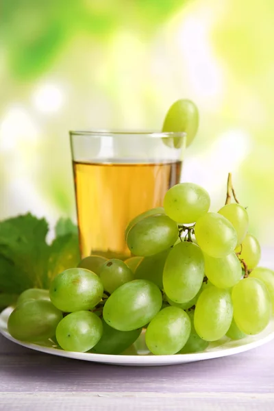 Bicchiere di succo d'uva su tavolo di legno su sfondo chiaro sfocato — Foto Stock