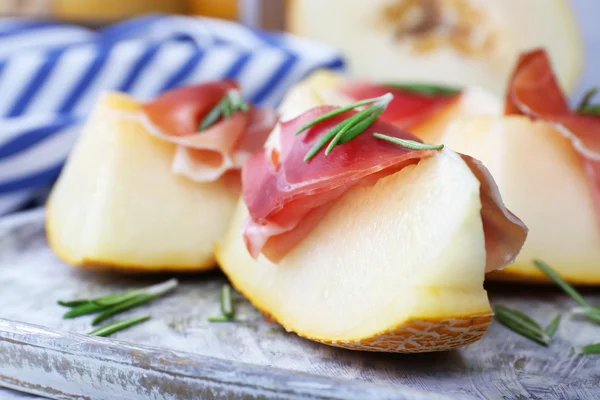 Melão com presunto de Parma em mesa de madeira, close-up — Fotografia de Stock