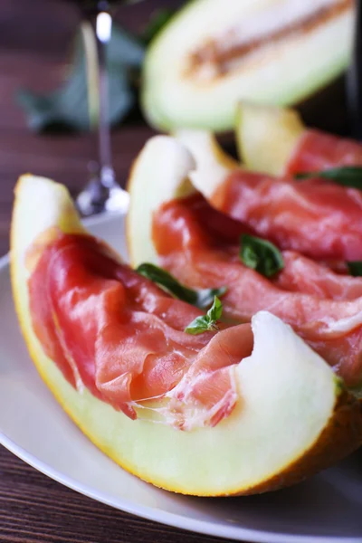 Melon with prosciutto of Parma ham on wooden table, closeup — Stock Photo, Image
