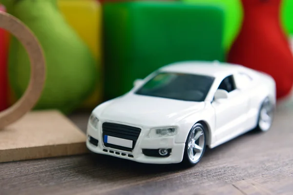 Small car with plastic toys on wooden table close up