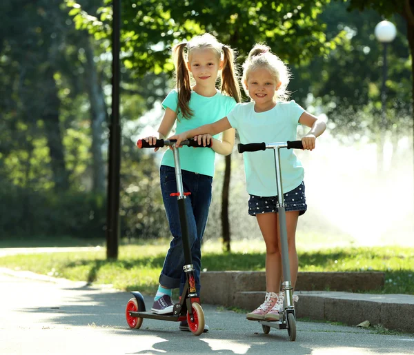 Small girls riding on scooters — Stock Photo, Image