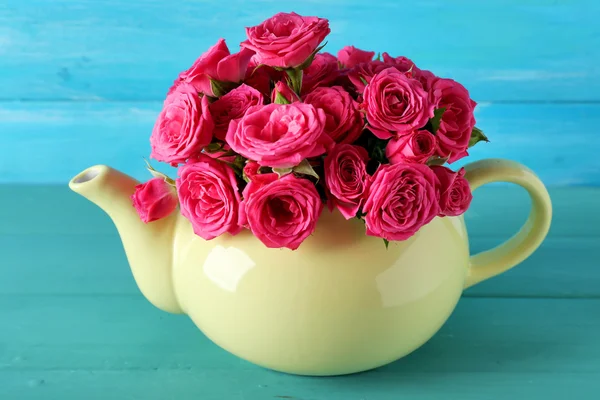 Belas rosas em bule de chá no fundo de madeira — Fotografia de Stock