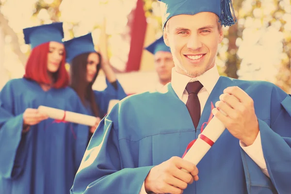 Graduated students in graduation hats and gowns, outdoors