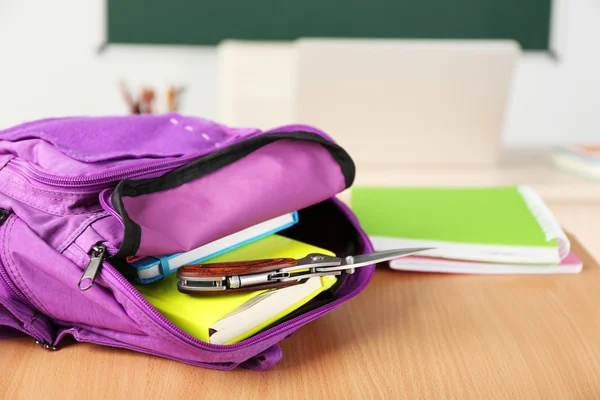 Backpack with knife in classroom, close up. Juvenile delinquency — Stock Photo, Image