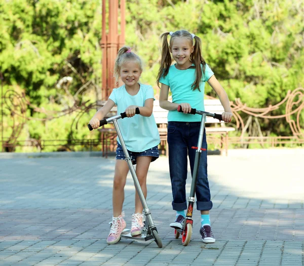 Meninas pequenas montando em scooters — Fotografia de Stock