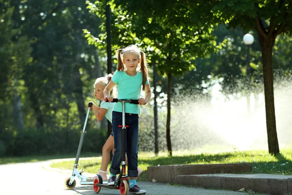 Kleine Mädchen fahren auf Rollern — Stockfoto