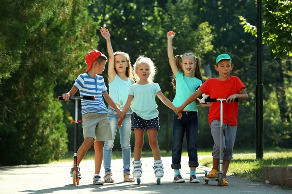 Enfants sur scooters et patins à roulettes — Photo