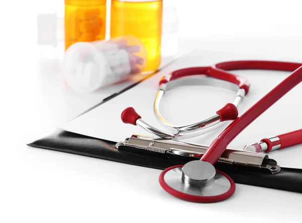 Medizinisches Stethoskop mit Klemmbrett und Tabletten isoliert auf weiß — Stockfoto