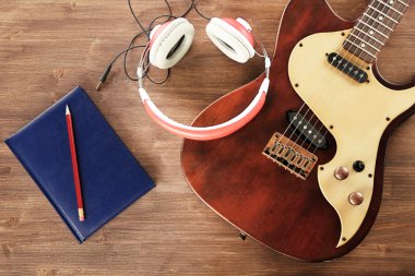 Elektro gitar ahşap masa üstünde defter ve kulaklık ile yakın çekim