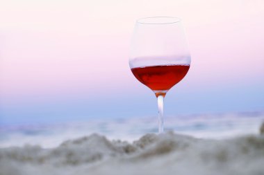 Romantik bir bardak şarap renkli gün batımında sahilde oturmuş