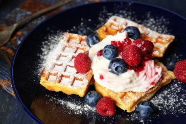 Orman meyveleri ve koyu ahşap arka plan üzerinde plaka üzerinde krema ile tatlı ev yapımı gözleme