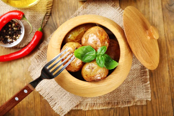 Batatas assadas na tigela na mesa de madeira, vista superior — Fotografia de Stock