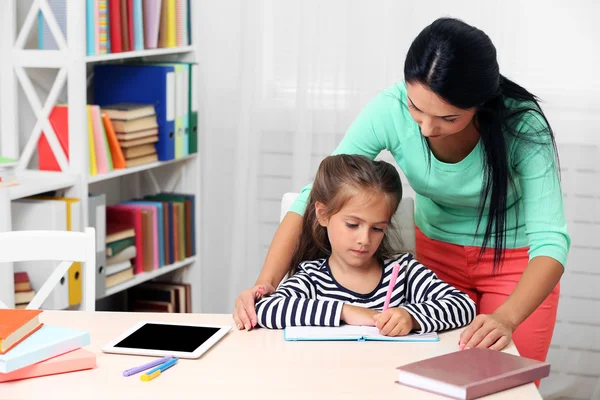 Schulmädchen macht Hausaufgaben mit Mutter — Stockfoto