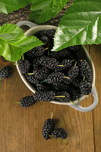 Moras maduras en tazón con hojas verdes en la mesa de cerca —  Fotos de Stock