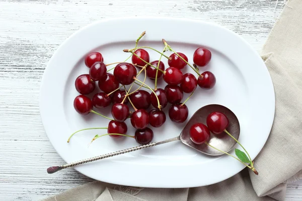 Sweet cherries on plate, on wooden background — Stock Photo, Image