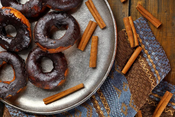 Delicious doughnuts with chocolate icing and cinnamon on table close up — Stock Photo, Image